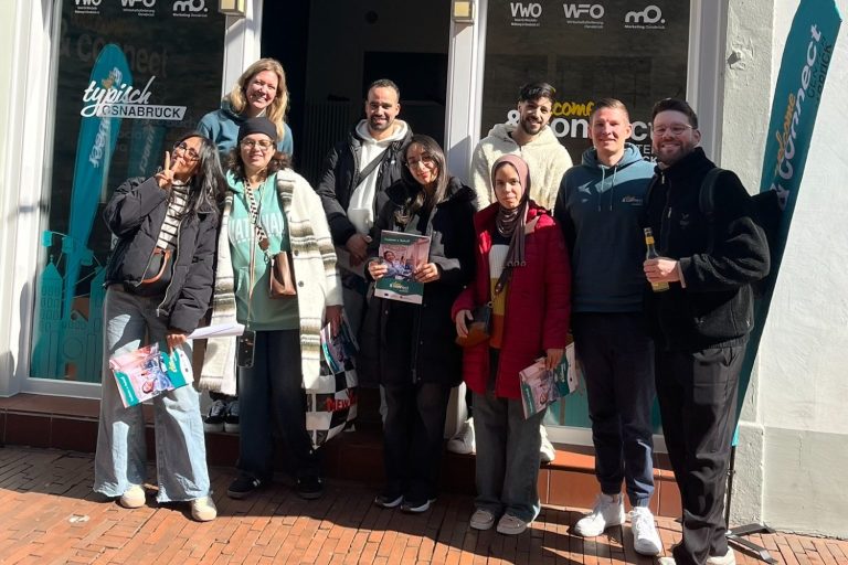 Frau in einem Riesenrad mit Blick auf die Stadt und Sonnenuntergang im Hintergrund.