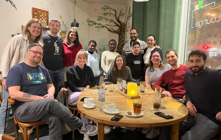 Eine Gruppe von Menschen sitzt in einer modernen Umgebung mit orangefarbenen Sofas.