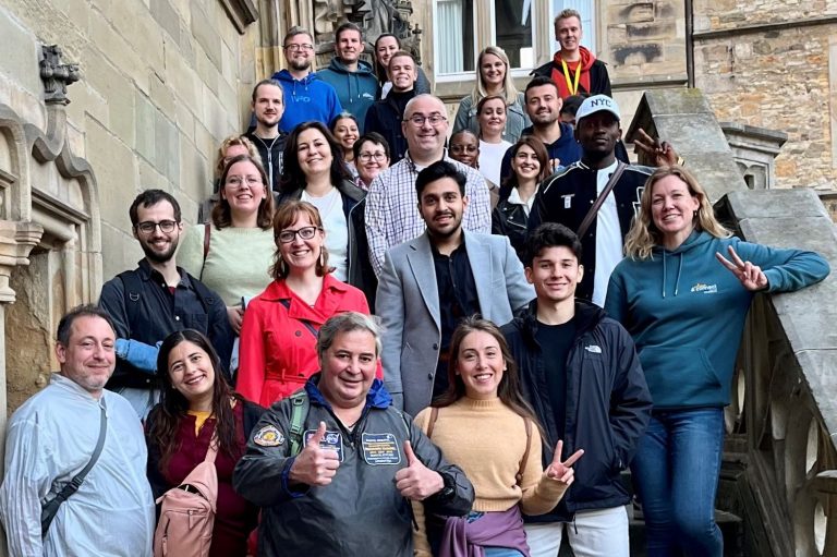 Eine Gruppe von 15 Personen steht auf einer Treppe, umgeben von historischem Mauerwerk.